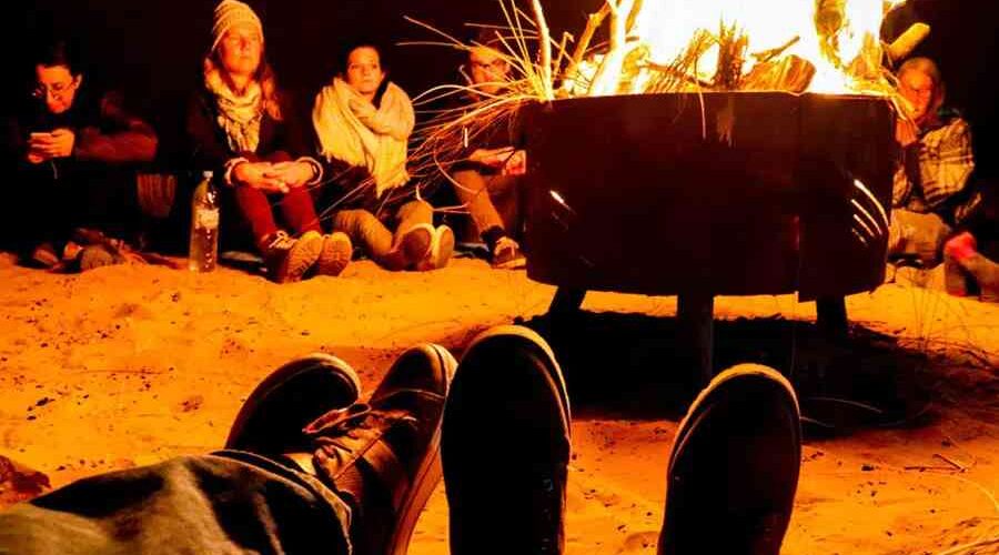 Travelers gathered around a campfire in the Sahara Desert at night.