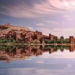 Sunset view of Kasbah Ait Ben Haddou reflected in still water, iconic stop on group Marrakech to Merzouga 3-day tour.