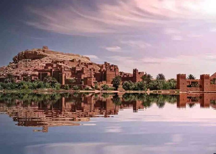 Kasbah Ait Ben Haddou world heritage village at sunrise with the adobe buildings reflection on the nearby rivier separating the village from the main road.