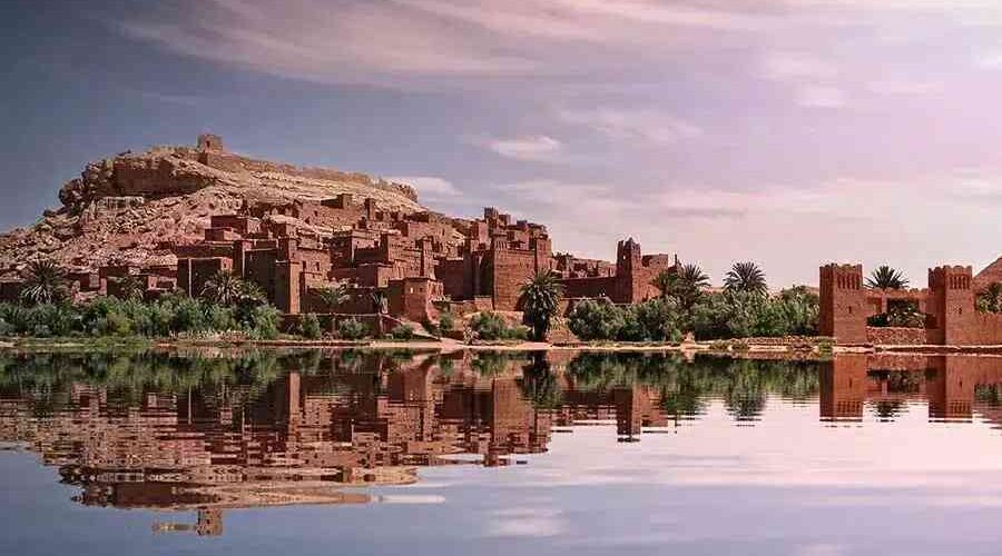 Kasbah Ait Ben Haddou world heritage village at sunrise with the adobe buildings reflection mirrored in the nearby rivier separating the village from the main road.
