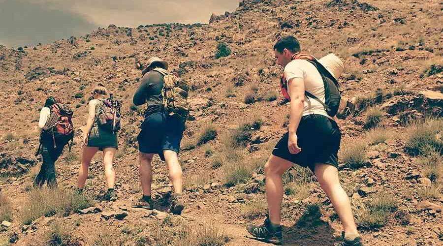 A group of hikers ascending a rocky trail on the Imlil to Ourika Valley trek in the Atlas Mountains.