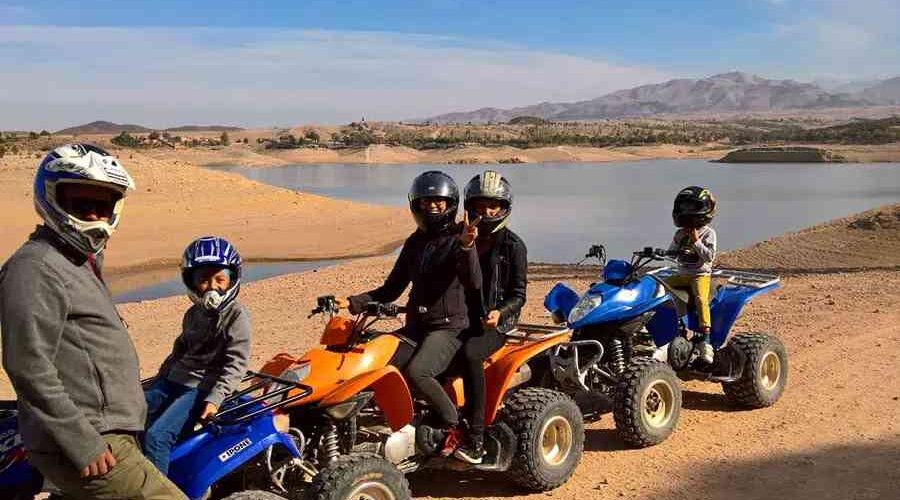 A family enjoying a quad bike tour beside Lalla Takerkouste lake in the Agafay Desert.