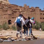 A group of friends crossing the river to Kasbah Ait Ben Haddou on their shared Marrakech to Fes desert tour