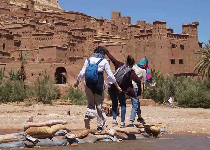 A group of friends crossing the river to Kasbah Ait Ben Haddou on their shared Marrakech to Fes desert tour