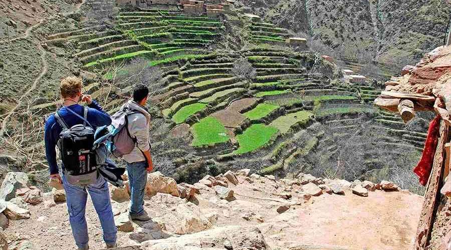 Two hikers observing terraced agriculture in the Atlas Mountains on a day trip from Marrakech
