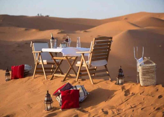 Intimate desert dining on sandy dunes during a private 3-day Marrakech to Merzouga tour.