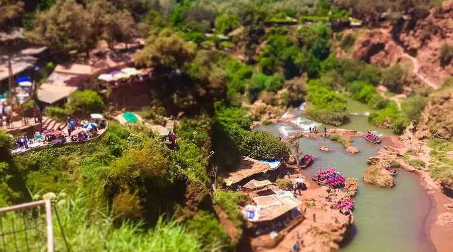 Lively river scene with traditional boats and riverside cafes at the base of Ouzoud Falls.