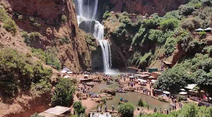 A panoramic view of Ouzoud Waterfalls with surrounding cafes and natural landscape.