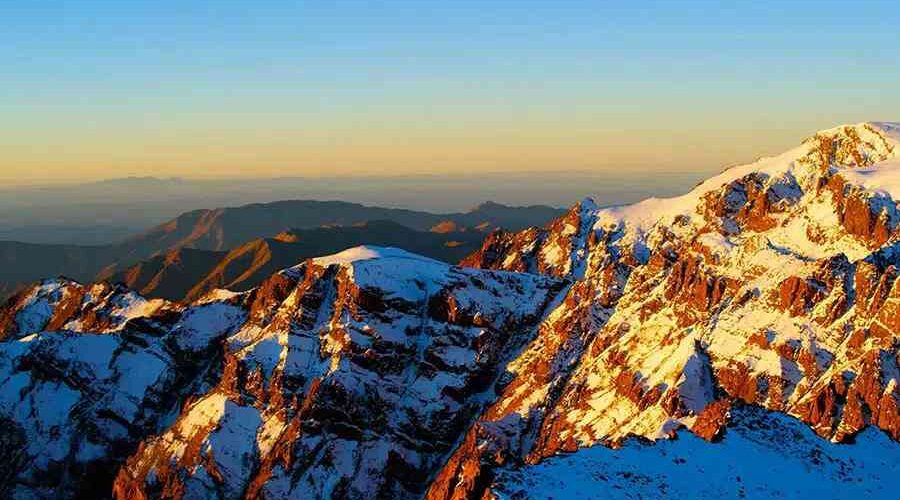 Sunset hues casting a warm glow over the snow-capped peaks of Mount Toubkal.