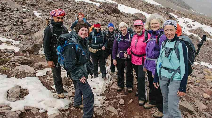A group of hikers on rocky terrain with snow patches during the 4-Day Mount Toubkal Trek.