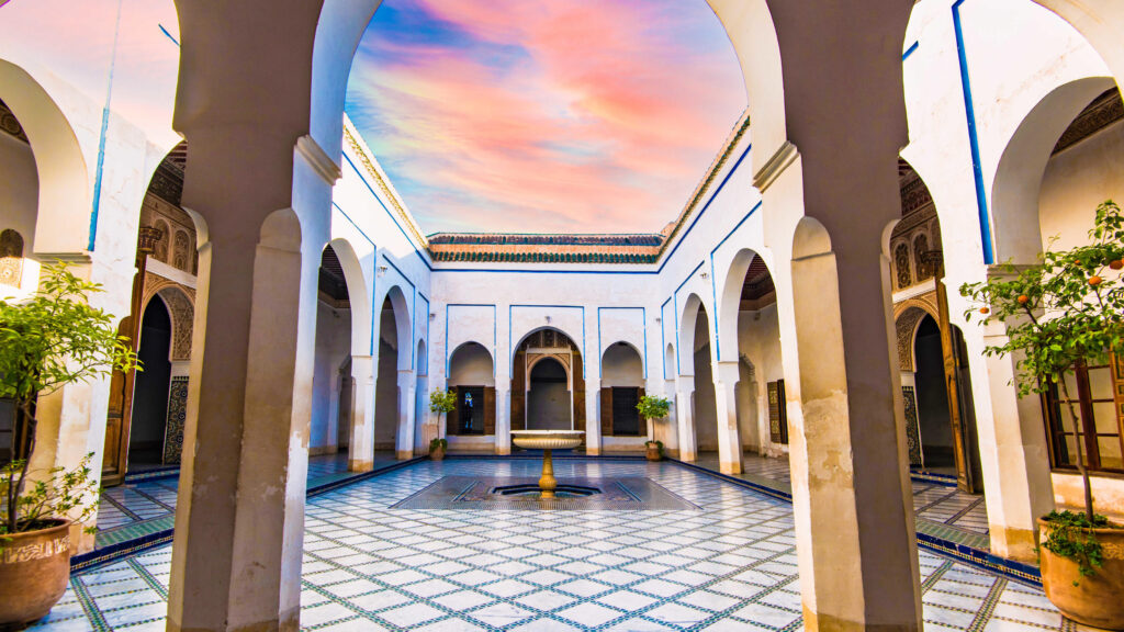 Stunning Bahia Palace courtyard with blue skies, detailed arches, and ornate zellige tilework reflecting Moroccan craftsmanship.