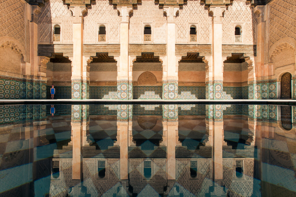 Symmetrical view of the intricately decorated courtyard of Ali Ben Youssef Madrasa with reflection in the central pool, Marrakech.