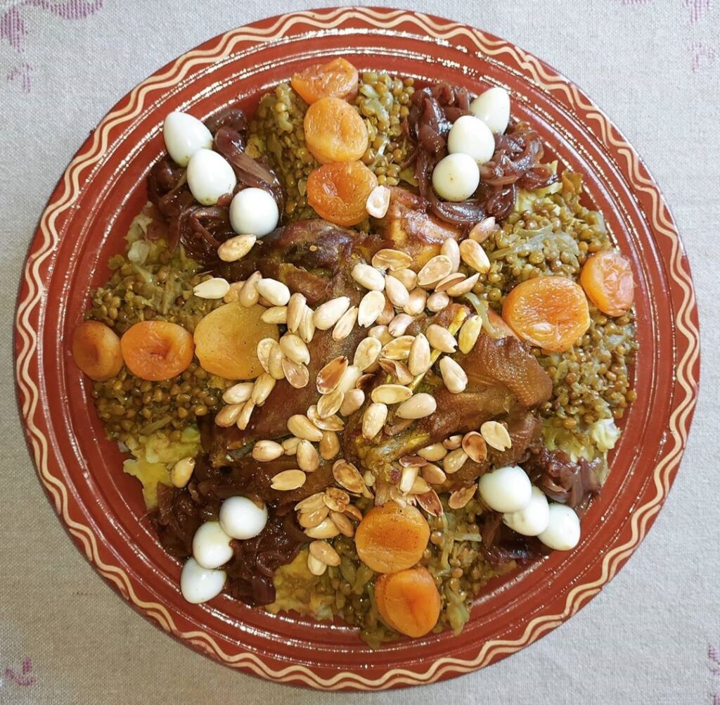 Moroccan Rfissa dish with chicken, lentils, and fenugreek seeds, garnished with almonds and apricots.