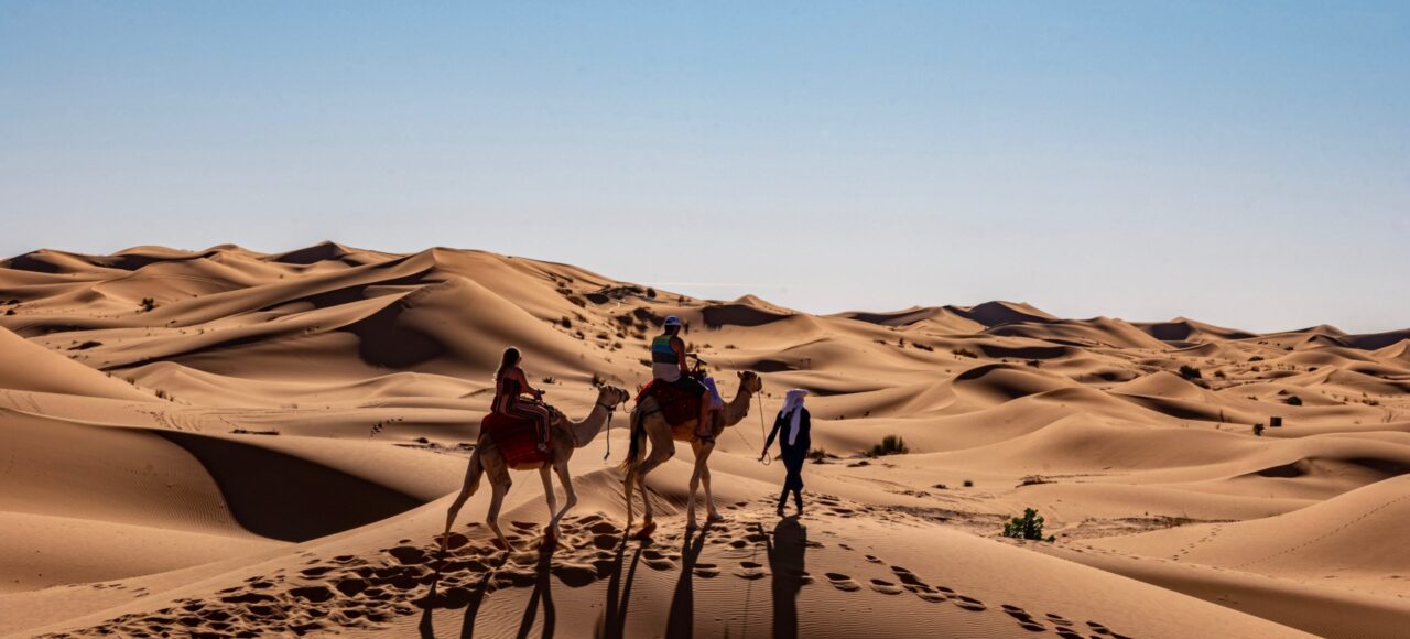 Camel caravan meandering through the majestic dunes of Erg Chigaga in Morocco's Sahara Desert.