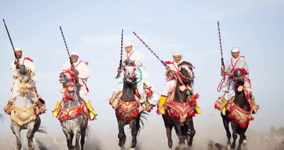 Moroccan horsemen in traditional attire performing the Fantasia, a cultural equestrian display.