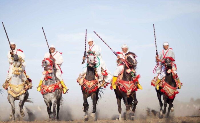 Moroccan horsemen in traditional attire performing the Fantasia, a cultural equestrian display.