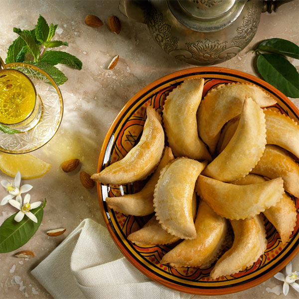 Freshly baked Moroccan Kaab el Ghazal pastries on a traditional ceramic plate.


