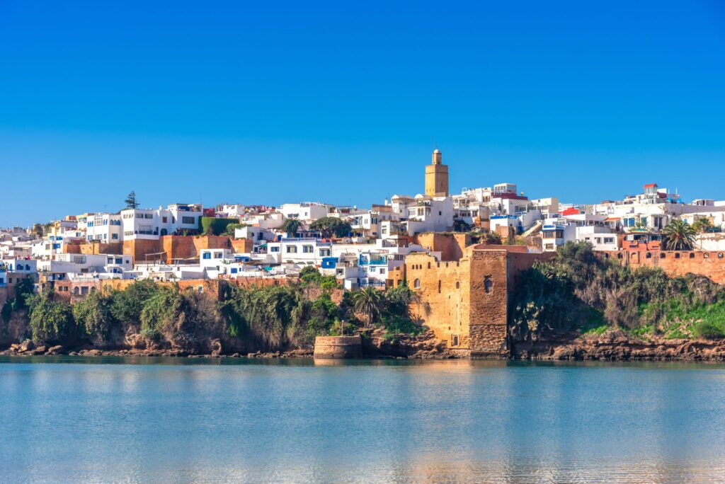 View of the ancient Kasbah Udaya along the Bouregreg river in Rabat, Morocco, showcasing historical architecture against modern white buildings under blue skies.