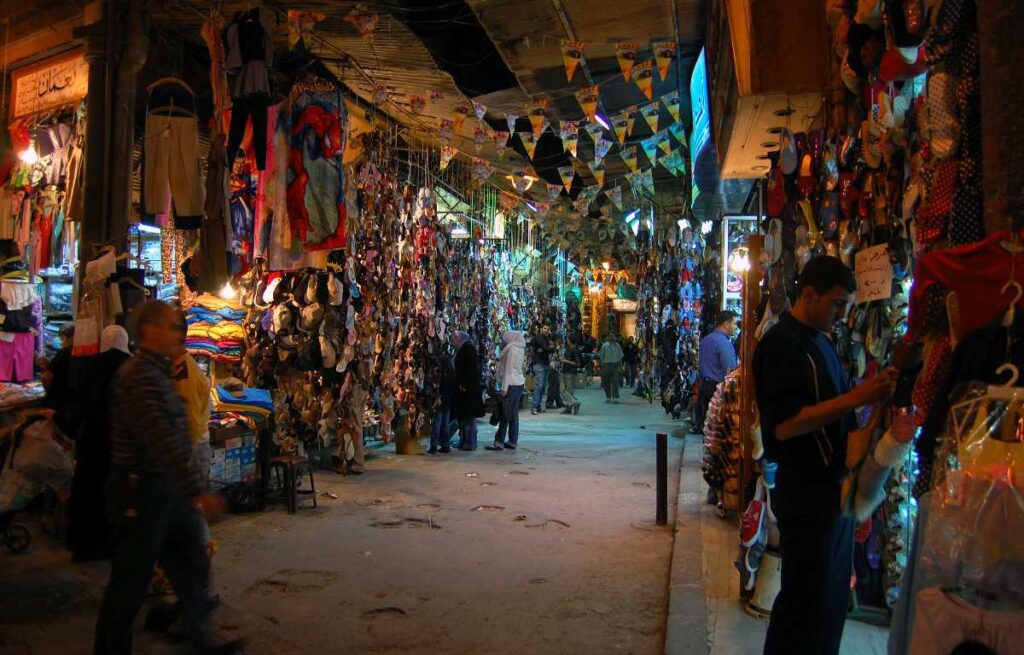Bustling Marrakech souk at night with colorful merchandise on display and locals browsing the stalls.