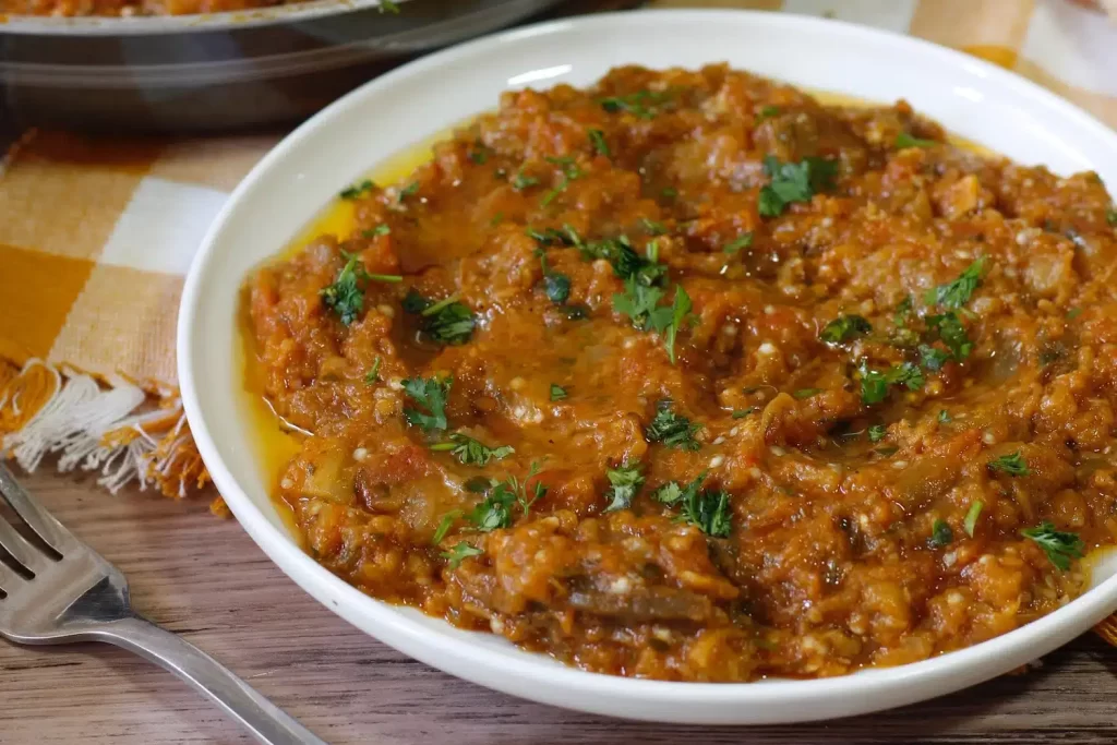 Hearty Moroccan Zaalouk with fresh parsley in a white serving dish, ready to enjoy.