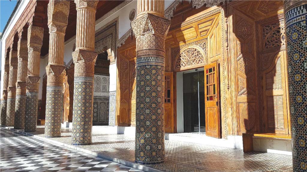 Corridor of Dar El Bacha Museum with elaborate columns and ornamental tile work in Marrakech.
