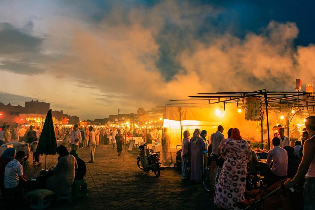 Vibrant evening markets in Morocco during Ramadan with food stalls emitting smoke and locals enjoying the festivity after sunset.