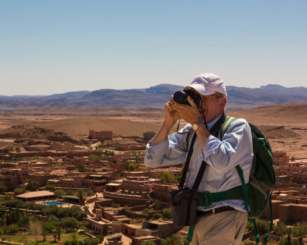 Man photographing Kasbah Ait Ben Haddou under clear skies