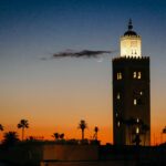 Silhouette of Koutoubia Mosque's minaret against a twilight sky with a crescent moon during Ramadan in Marrakech, Morocco.