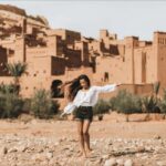 a lady posing for a photo in front of Kasbah Ait Ben Haddou
