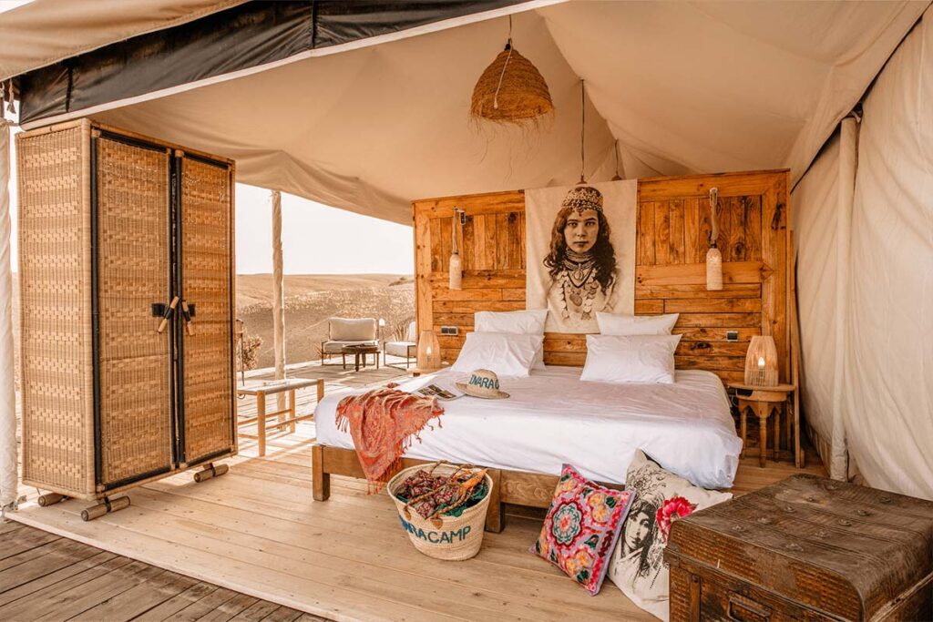 Cozy glamping tent interior with plush bedding and rustic wooden decor in the Agafay Desert.