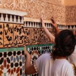 Tourists on a Marrakech guided walking tour admire the intricate Arabic calligraphy and tilework in the Medina.
