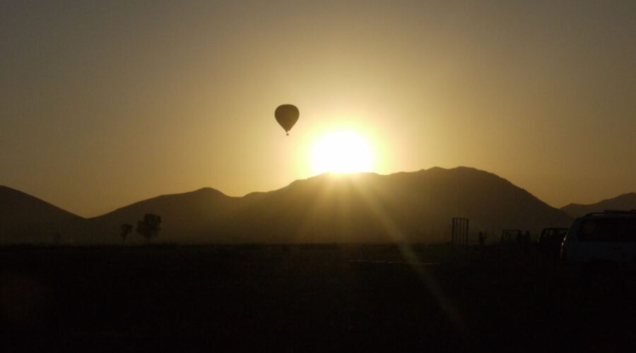 Silhouette of a hot air balloon against a radiant sunrise over the mountains near Marrakech.