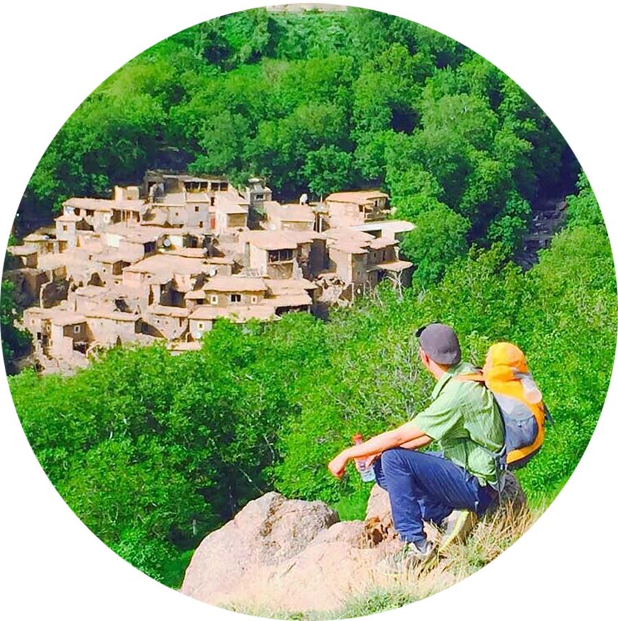 Two travelers gazing at an ancient Berber village nestled in lush greenery.