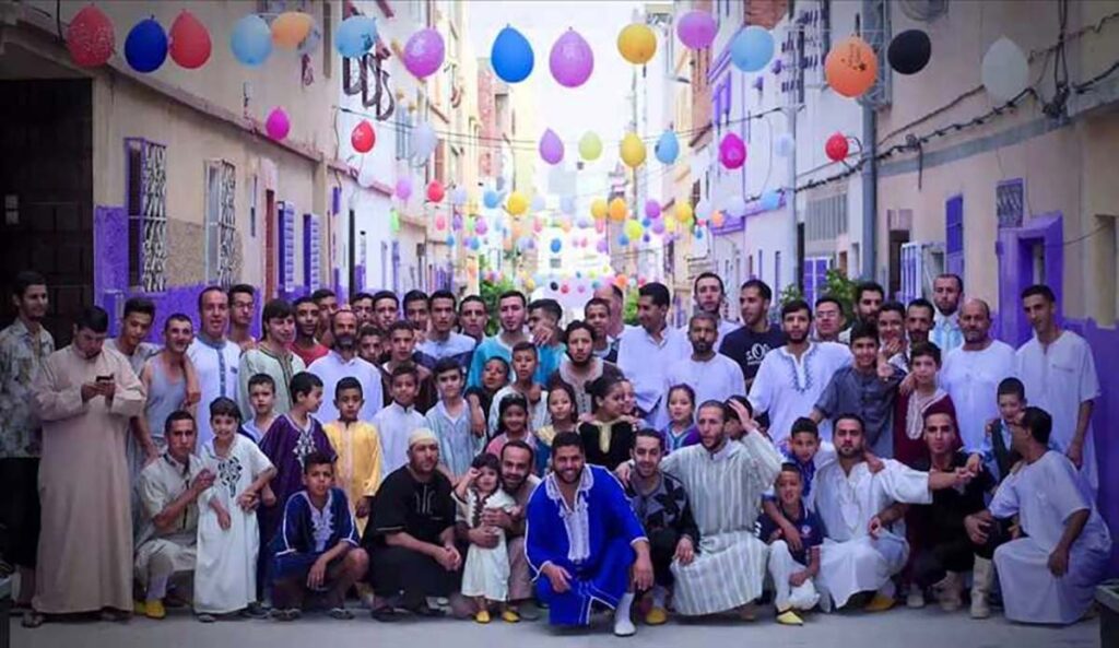 Community of Moroccan people celebrating Eid Al Fitr in a decorated street.