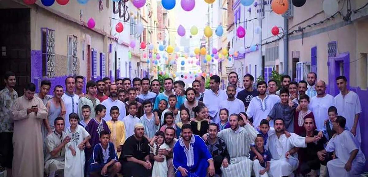 Community of Moroccan people celebrating Eid Al Fitr in a decorated street.