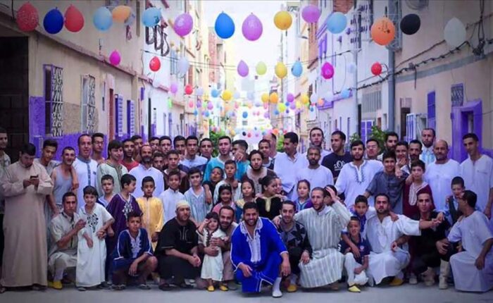 Community of Moroccan people celebrating Eid Al Fitr in a decorated street.