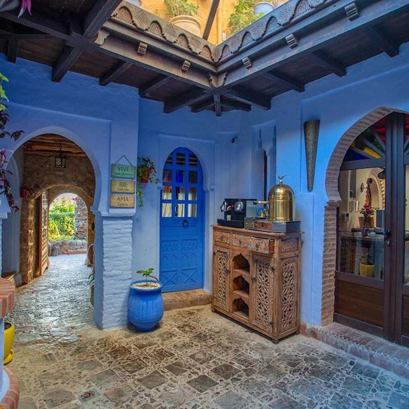 Cozy alleyway in a Chefchaouen riad painted in distinctive blue, featuring traditional Moroccan decor and a serene atmosphere.