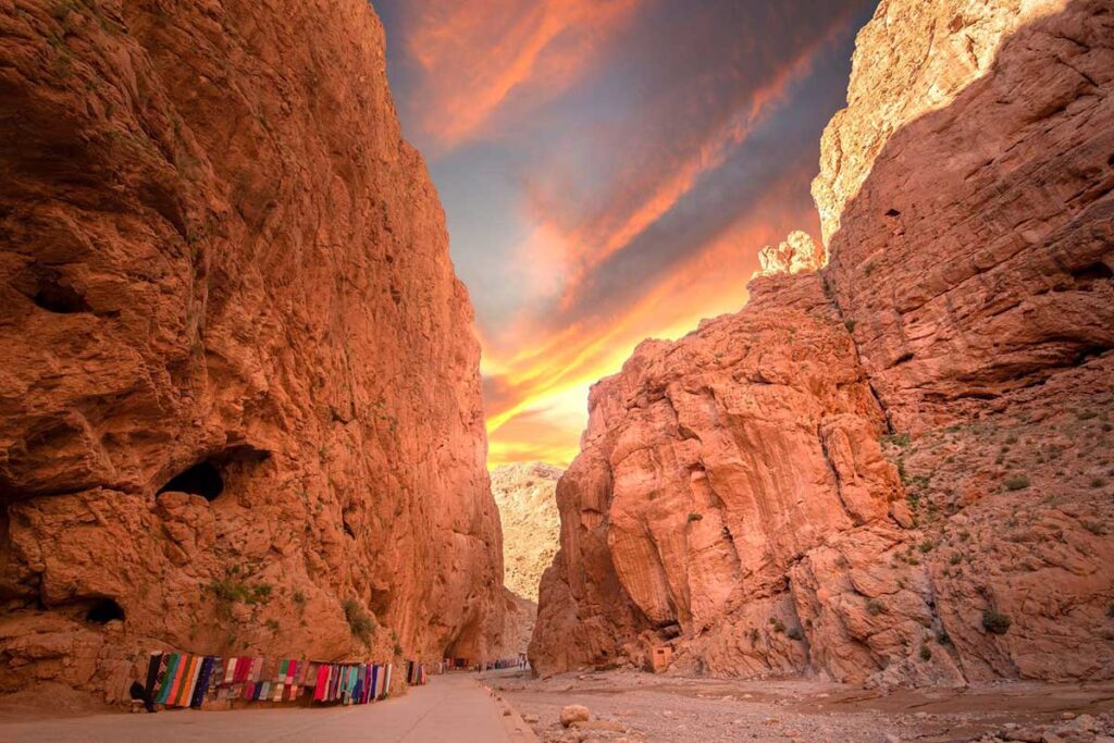 Golden sunrise lights 300 m Todgha Gorge cliffs & Berber rug stalls near Tinghir, Morocco