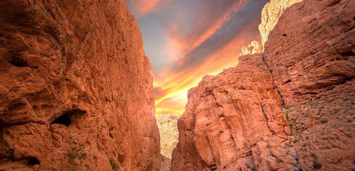 Golden sunrise lights 300 m Todgha Gorge cliffs & Berber rug stalls near Tinghir, Morocco