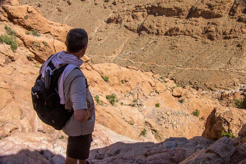 Hiker surveys rugged Todgha Valley from High Atlas overlook above the gorge.