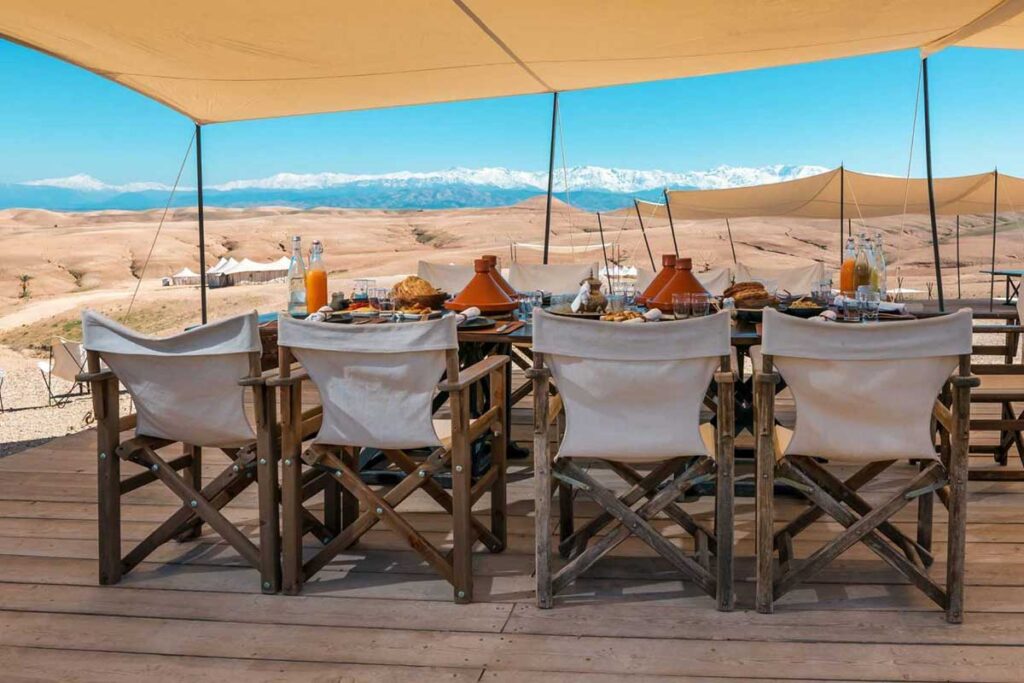 Moroccan tajine dinner setup in Agafay Desert with Atlas Mountains in the background.