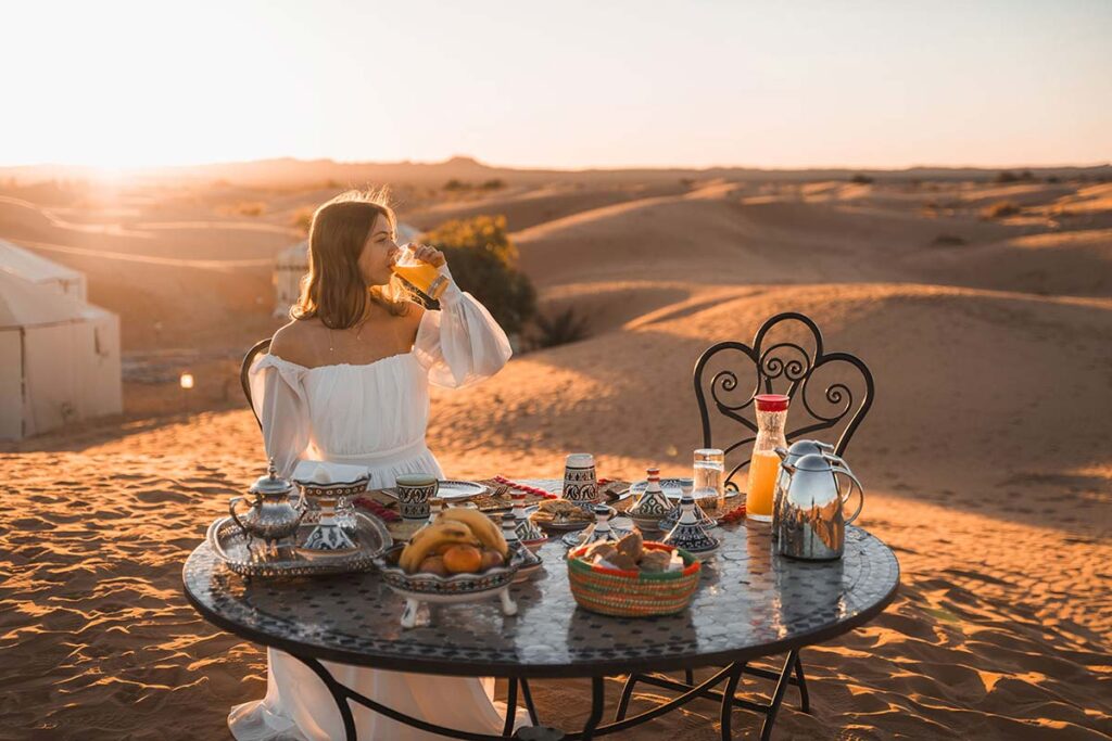 Sunrise breakfast in the dunes at a Merzouga luxury desert camp with Moroccan tea and fresh pastries