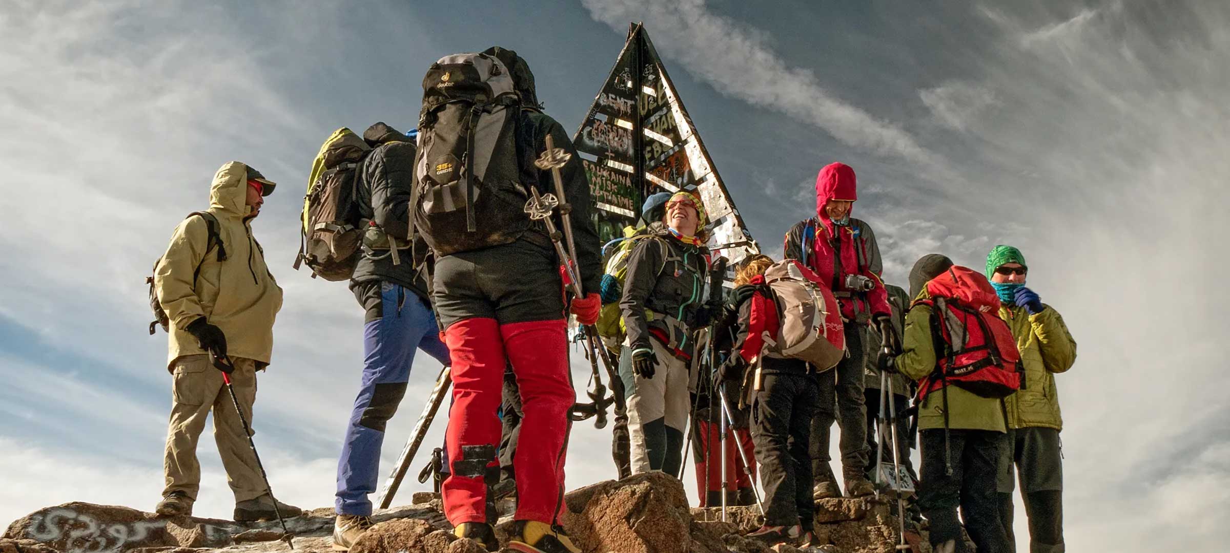 Trekkers at the Mount Toubkal summit marker (4,167m) at dawn on a 2-day trek from Marrakech
