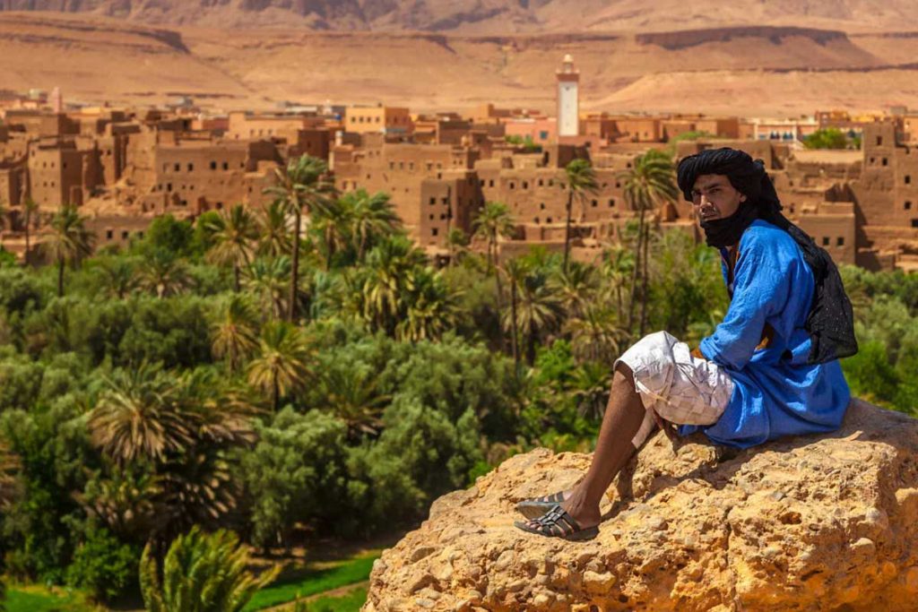 Berber man in a blue gandoura overlooking the Tinghir oasis and palm grove on a 3-day desert tour from Fes to Marrakech
