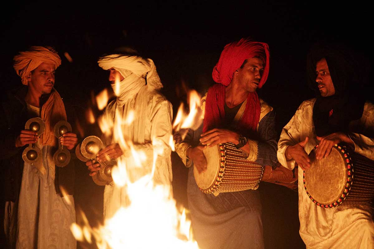 Berber musicians playing krakeb castanets and drums around a campfire during a Gnaoua performance in the Sahara on the 4-day Fes to Marrakech desert tour